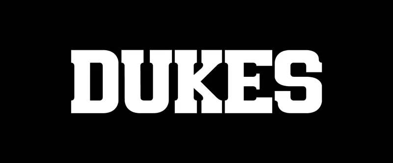 dukes nameplate is written in red angular text to look like slash marks in front of a black background.