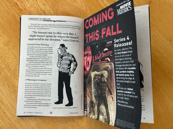 Prototype of the zine open face-up to display the end of an article on the left page and the action figure ad on the right. All is presented on a wood table surface.